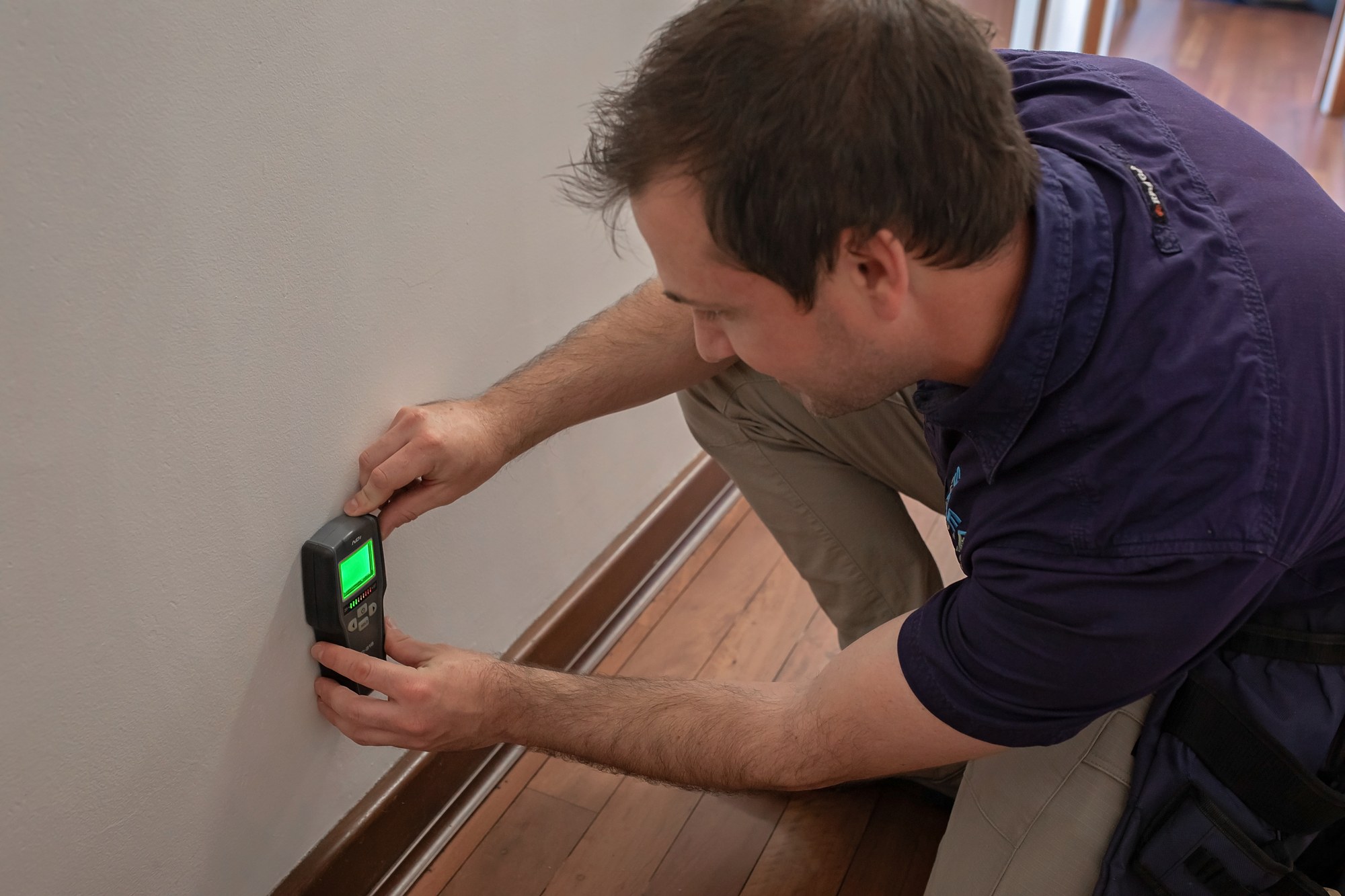 SURE inspector using a moisture meter on an interior wall