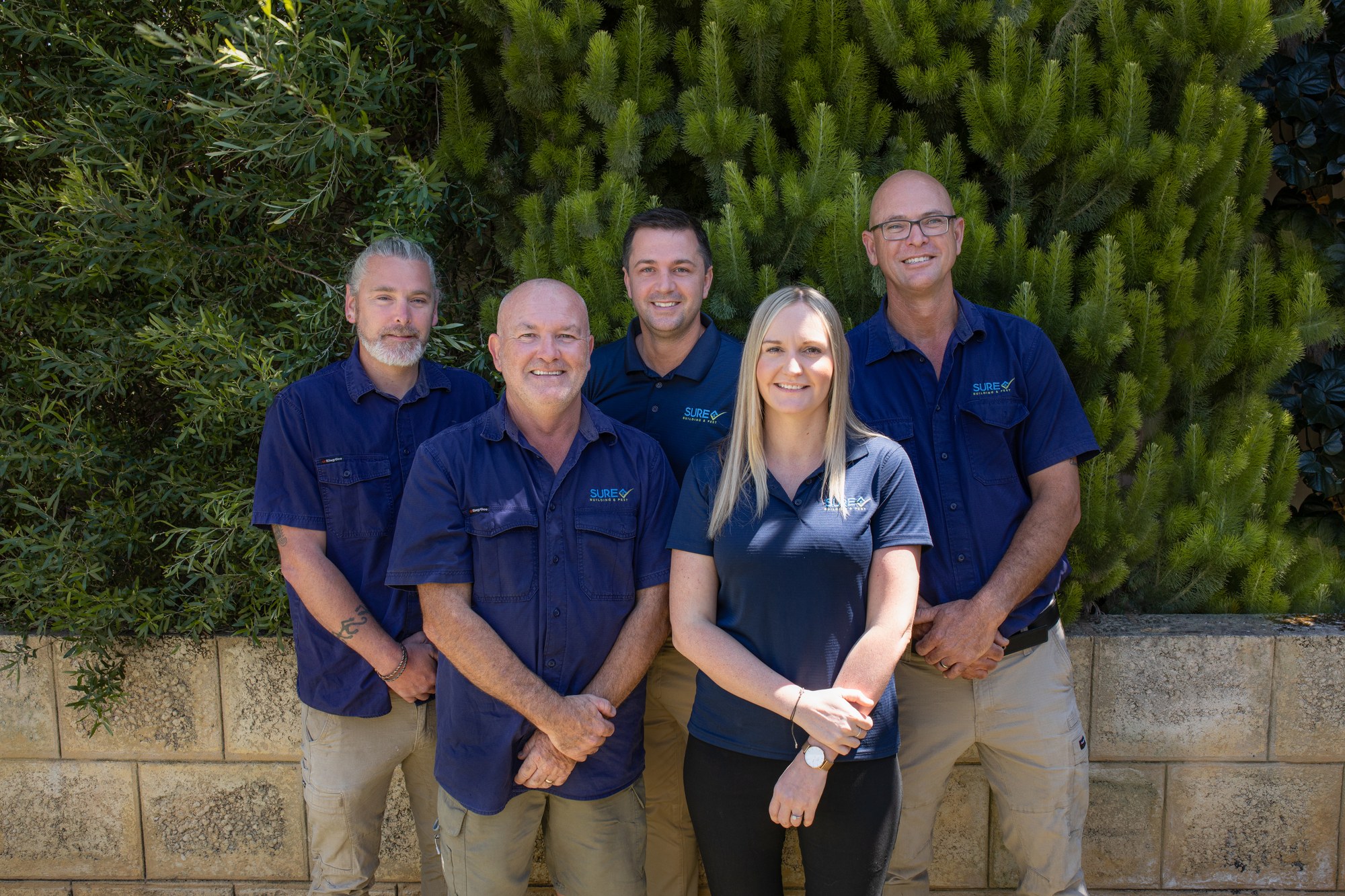 Five SURE team members in branded polos outdoors