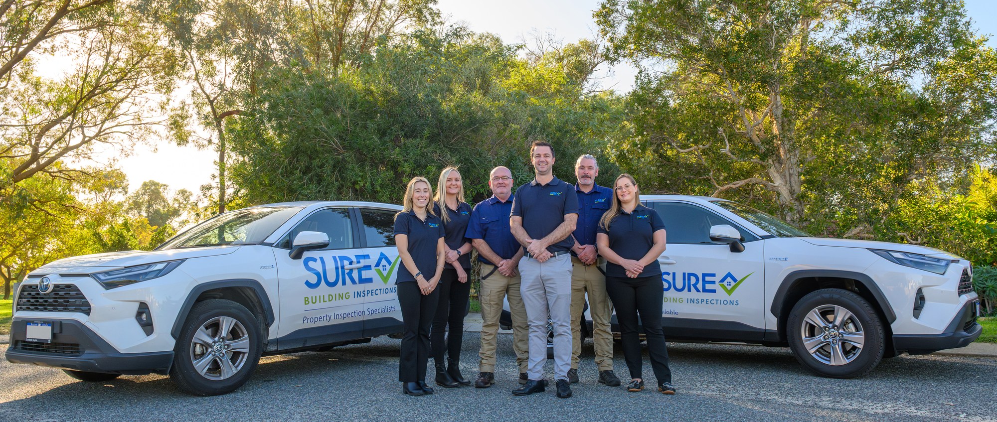 SURE team posed beside two branded inspection vehicles