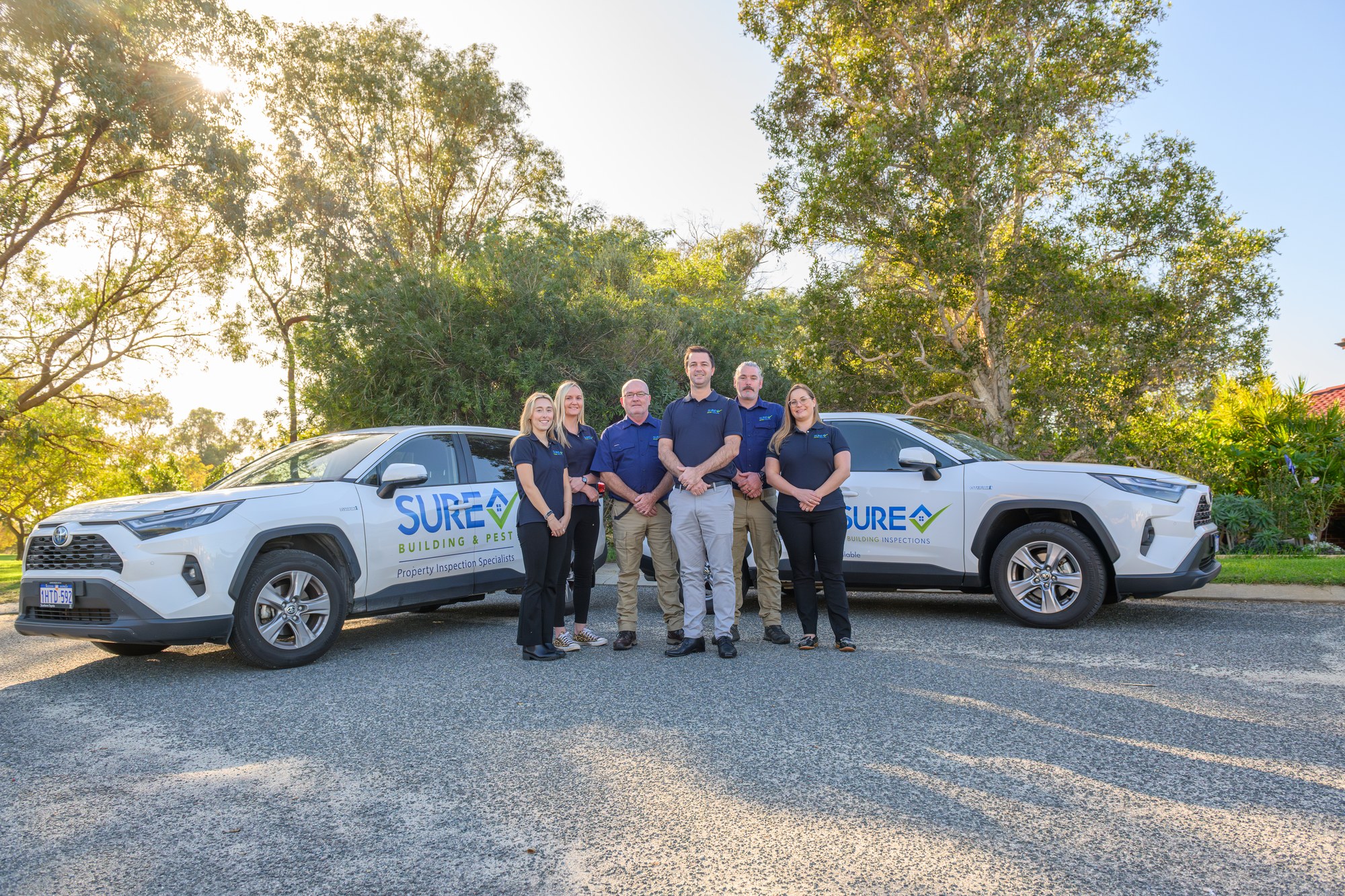 SURE team of six standing between two branded inspection SUVs