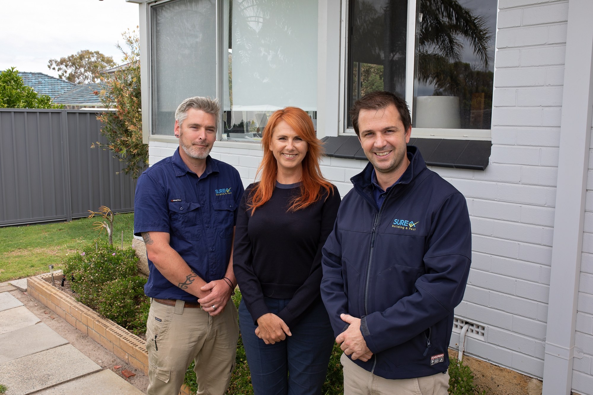 Two SURE staff with a client outside a home
